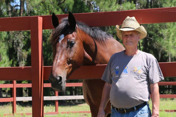 Volunteer Bob "the Builder" standing with Samson next to the round pen he fixed.